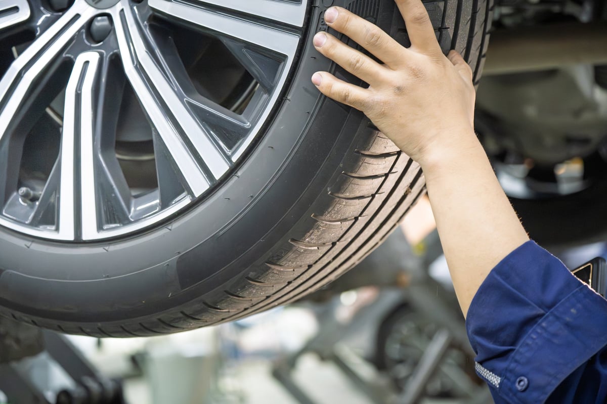 Technician inspecting a car tyre for uneven tread wear